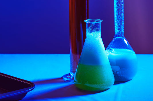 Beakers filled with blue and green liquids in a laboratory setting, representing retinol research and science.